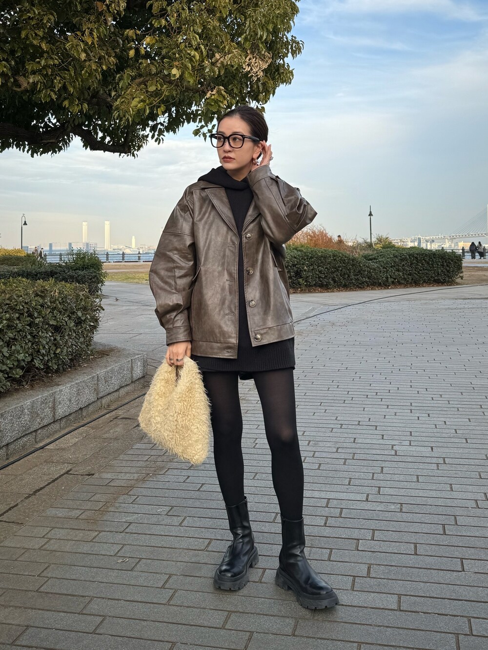 ブラウン系のブルゾン、ブラック系のブーツを着用したレディースの冬コーディネートの2枚目の写真