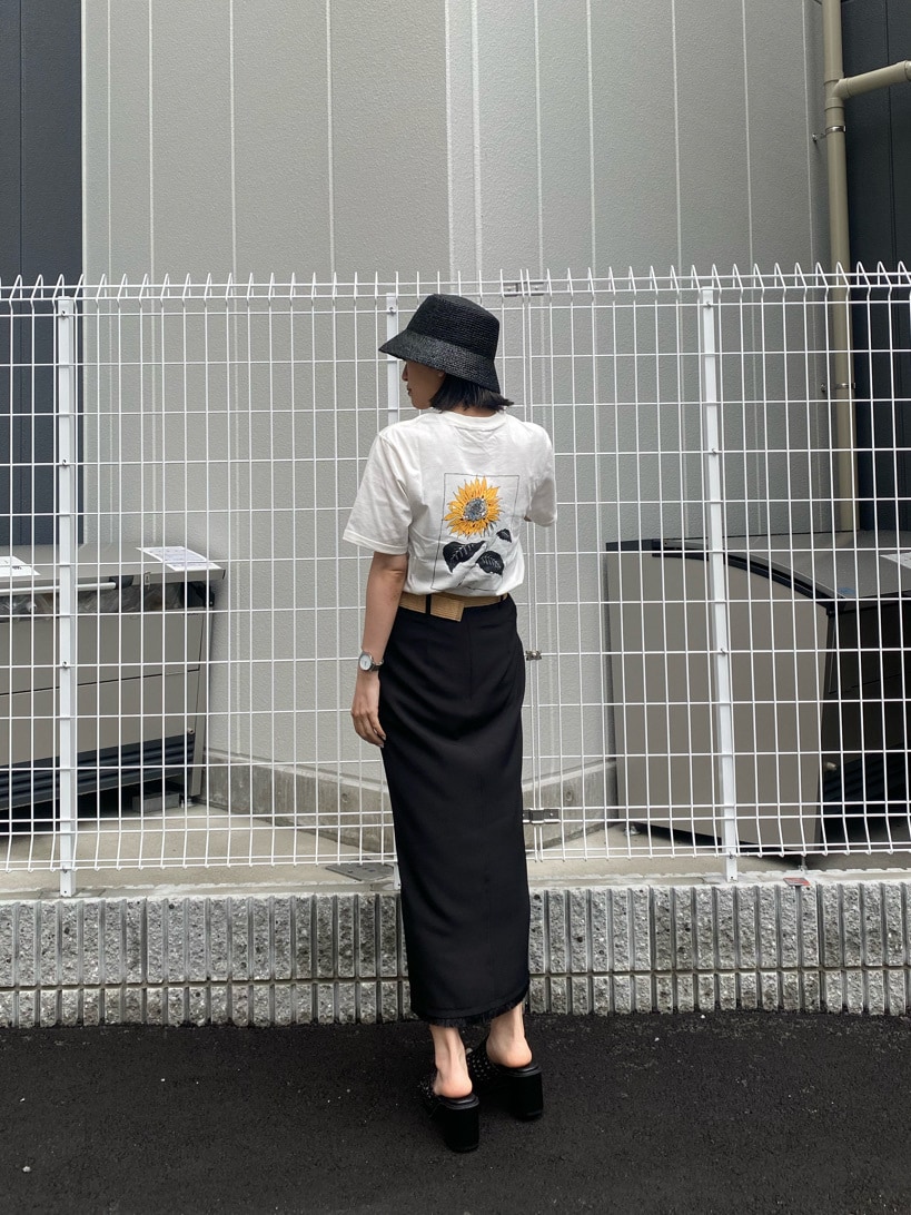 ブラック系のスカート、ブラック系のサンダル、ホワイト系のTシャツ/カットソーを着用したレディースの春コーディネートの2枚目の写真