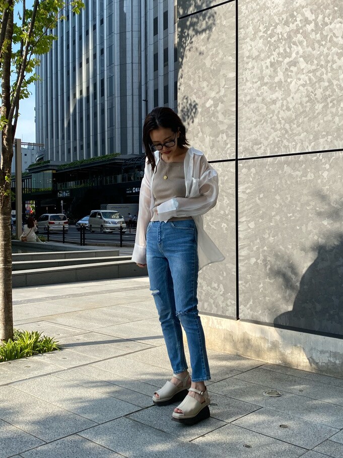 ホワイト系のサンダル、ブルー系のデニムパンツ、ベージュ系のニット/セーターを着用したレディースの春コーディネートの4枚目の写真