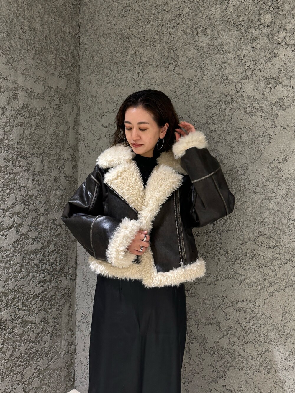 ブラック系のスカート、ブラック系のブーツ、ブラウン系のムートンコートを着用したレディースの夏コーディネートの5枚目の写真