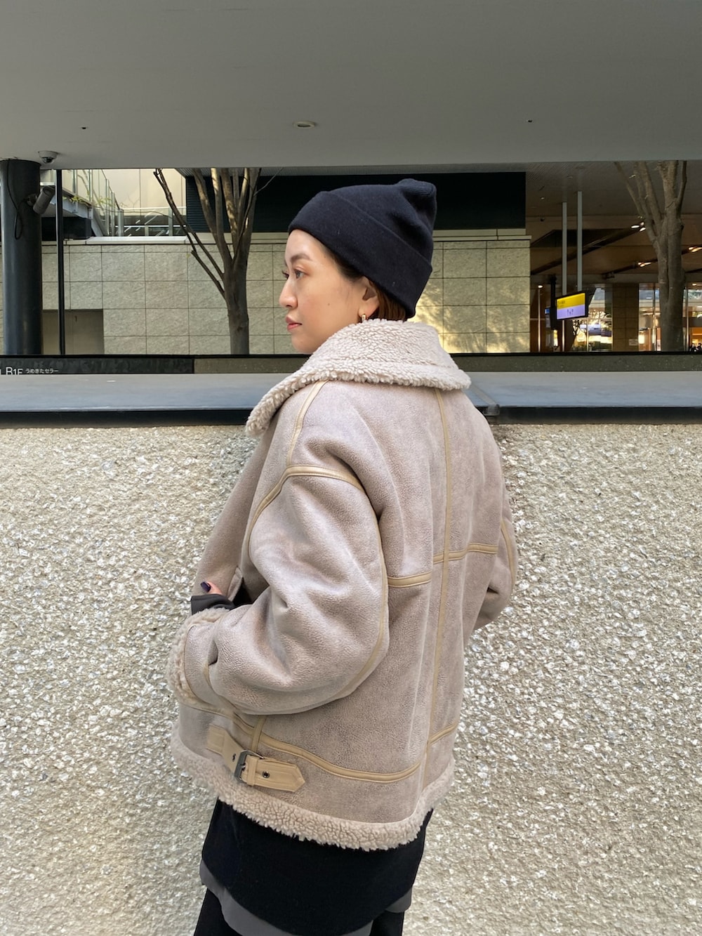 ベージュ系のムートンコート、ブラック系のニット/セーター、ブラック系のブーツを着用したレディースの秋コーディネートの7枚目の写真