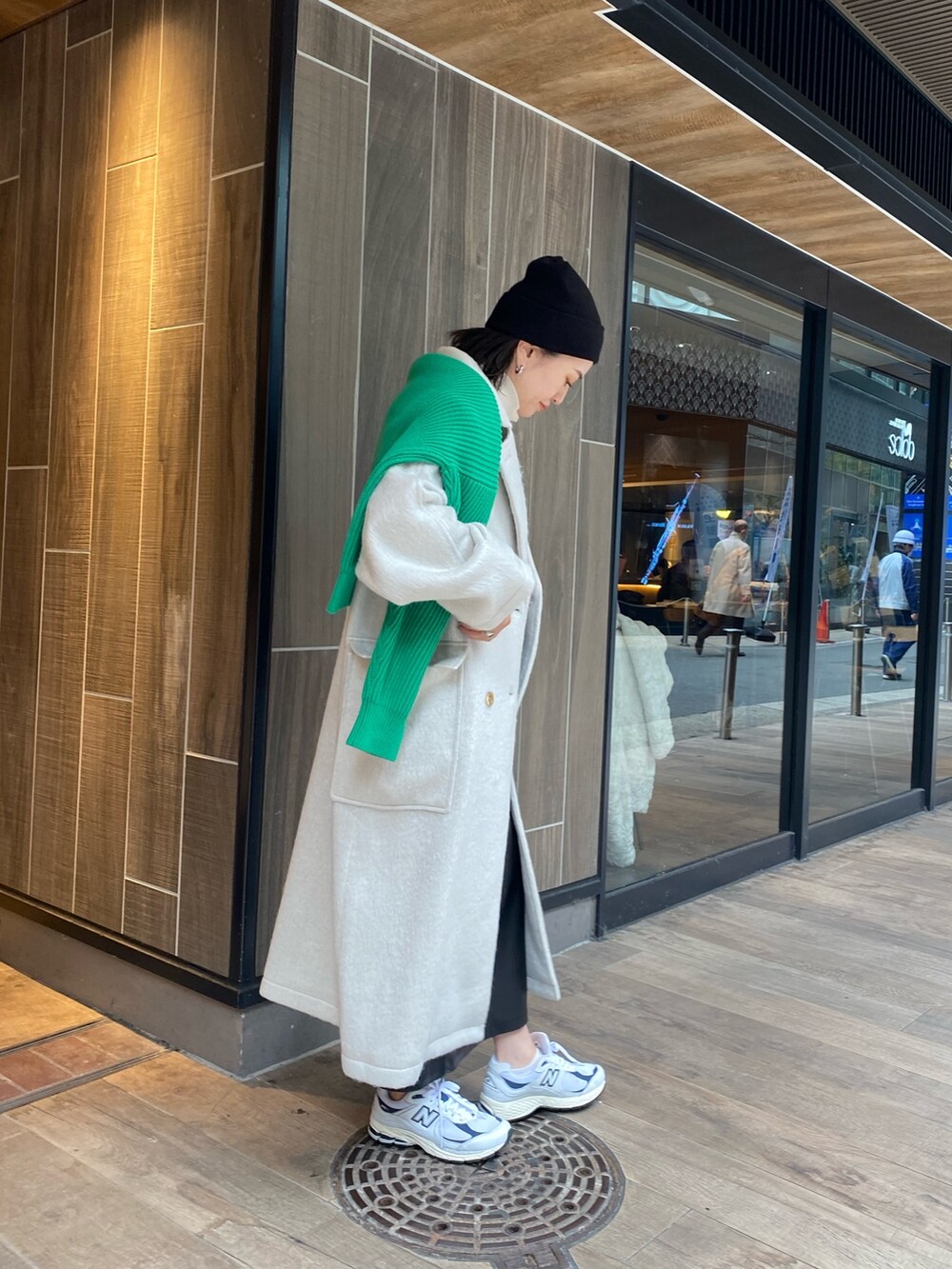 グリーン系のニット/セーター、ホワイト系のチェスターコート、ホワイト系のニット/セーターを着用したレディースの冬コーディネートの2枚目の写真