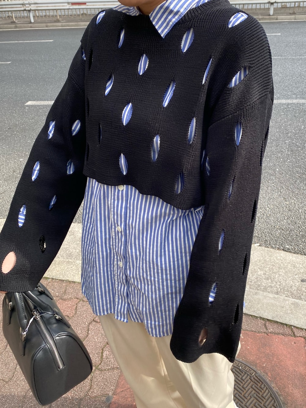 ブラック系のニット/セーター、ブラック系のハンドバッグを着用したレディースの冬コーディネートの6枚目の写真