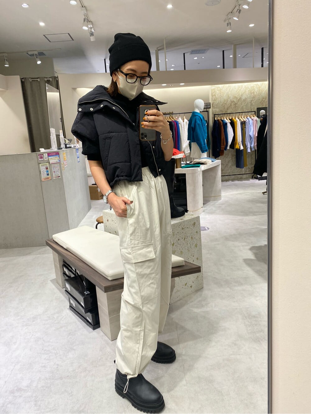 ブラック系のダウンベスト、ブラック系のニット/セーター、ホワイト系のカーゴパンツを着用したレディースの秋コーディネートの2枚目の写真