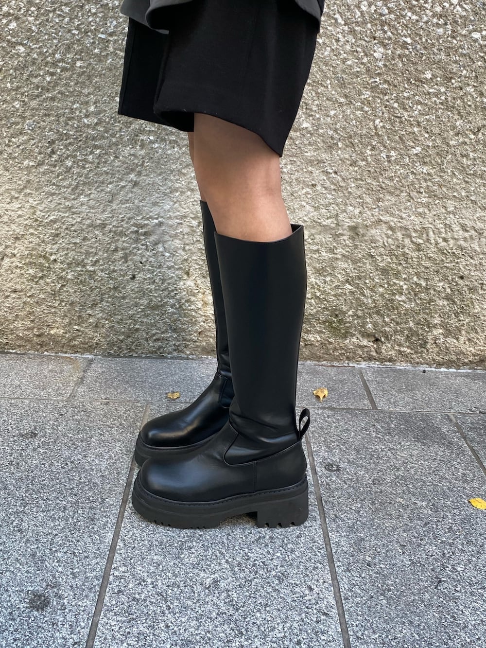 ベージュ系のムートンコート、ブラック系のニット/セーター、ブラック系のブーツを着用したレディースの秋コーディネートの4枚目の写真