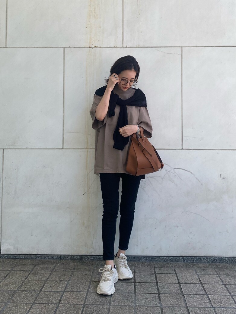 ブラック系のニット/セーター、ベージュ系のTシャツ/カットソー、ブラック系のデニムパンツを着用したレディースの春コーディネートの2枚目の写真