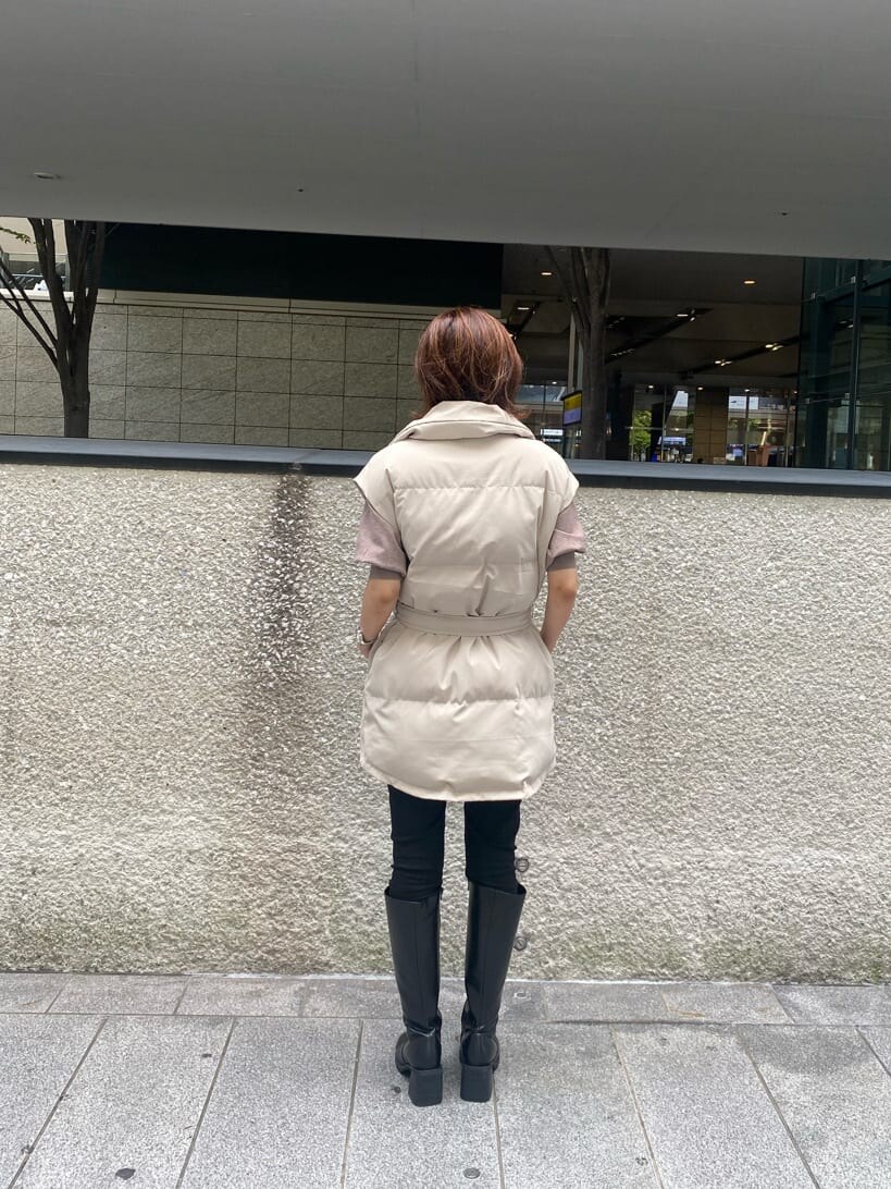 ブラック系のデニムパンツ、ベージュ系のニット/セーター、ホワイト系のダウンベストを着用したレディースの秋コーディネートの5枚目の写真