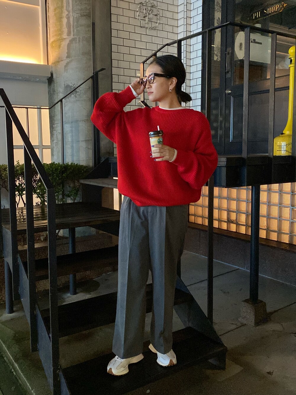 グレー系のスラックス、レッド系のニット/セーターを着用したレディースの秋コーディネートの2枚目の写真