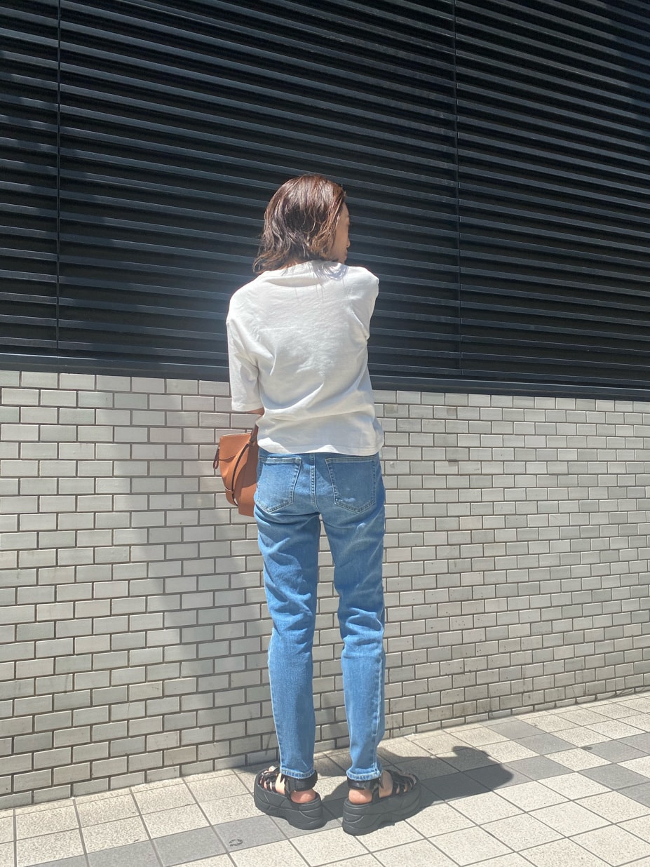 ブルー系のデニムパンツ、ブラック系のサンダル、その他のTシャツ/カットソーを着用したレディースの春コーディネートの4枚目の写真