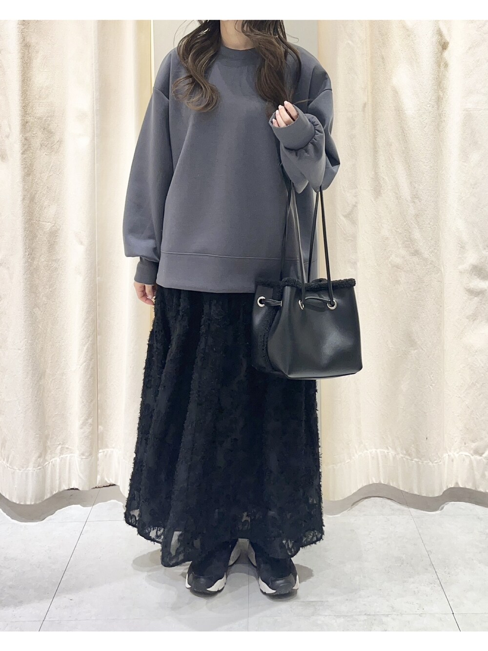 グレー系のTシャツ/カットソー、ブラック系のスカート、ブラック系のハンドバッグを着用したレディースの冬コーディネートの2枚目の写真