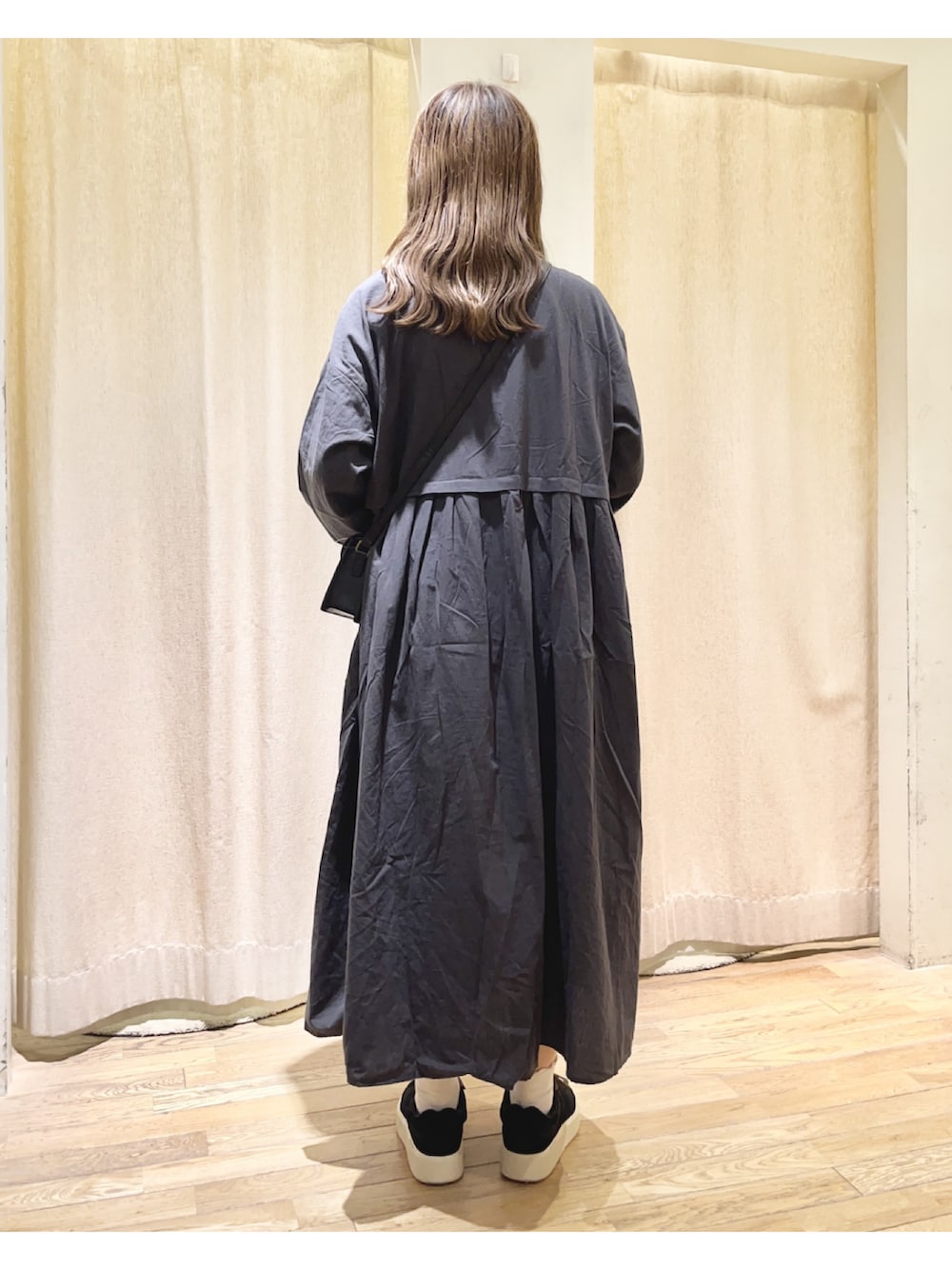 グレー系のワンピース、ブラック系のショルダーバッグ、ブラック系のスニーカーを着用したレディースの夏コーディネートの2枚目の写真