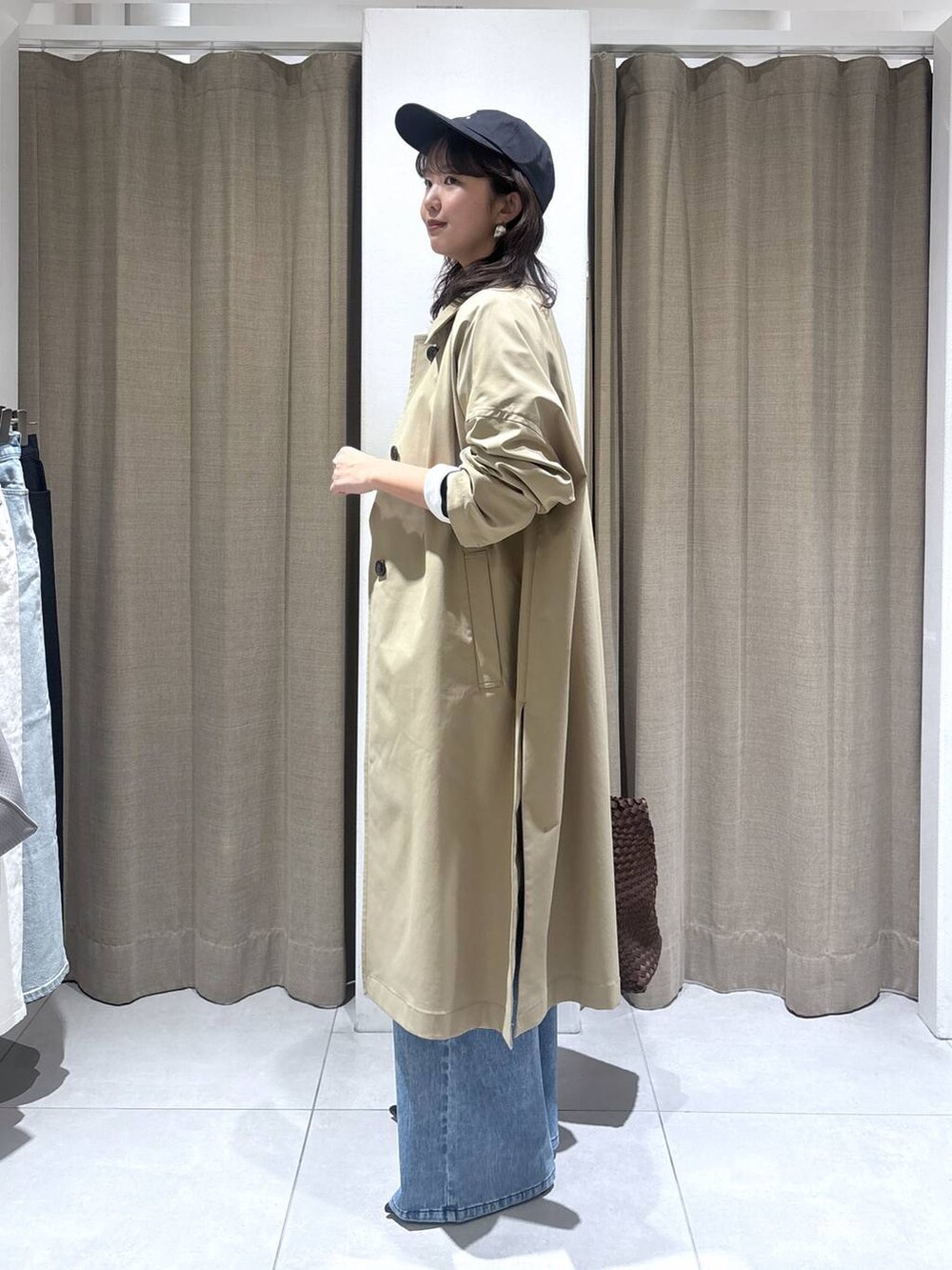 ホワイト系のTシャツ/カットソー、ブルー系のデニムパンツ、ベージュ系のステンカラーコートを着用したレディースの冬コーディネートの6枚目の写真