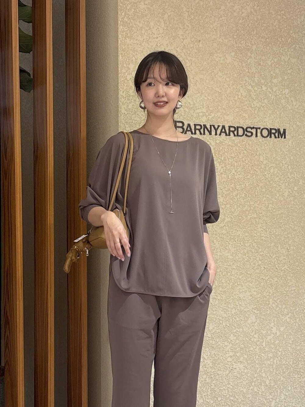 グリーン系のTシャツ/カットソー、ブラウン系のハンドバッグ、イエロー系のパンプスを着用したレディースの冬コーディネートの3枚目の写真