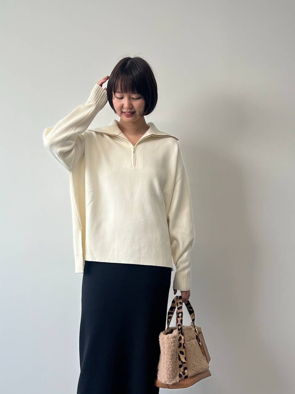 ブラウン系のトートバッグ、ブラック系のスカート、ブラック系のスニーカーを着用したレディースの冬コーディネートの2枚目の写真