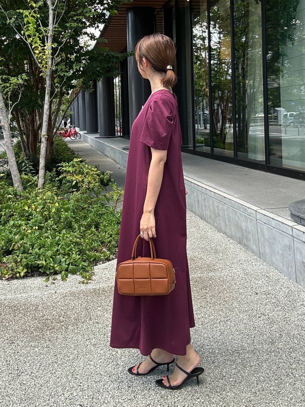 ブラック系のスリッポン、ブラウン系のハンドバッグ、レッド系のワンピースを着用したレディースの夏コーディネートの3枚目の写真