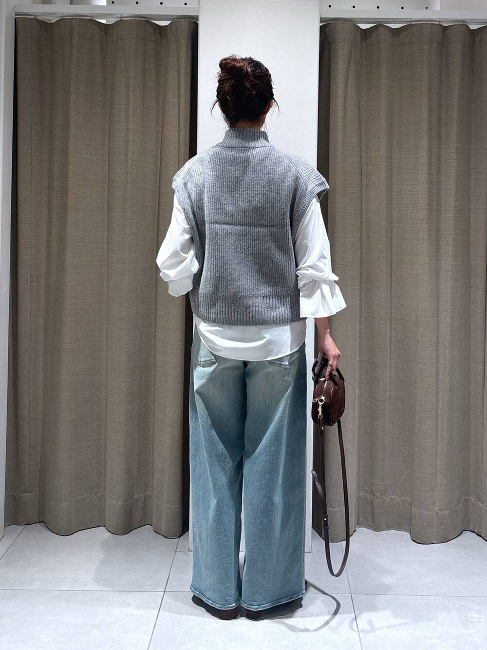 ブルー系のデニムパンツ、ホワイト系のシャツ/ブラウス、ブラウン系のショルダーバッグを着用したレディースの秋コーディネートの4枚目の写真