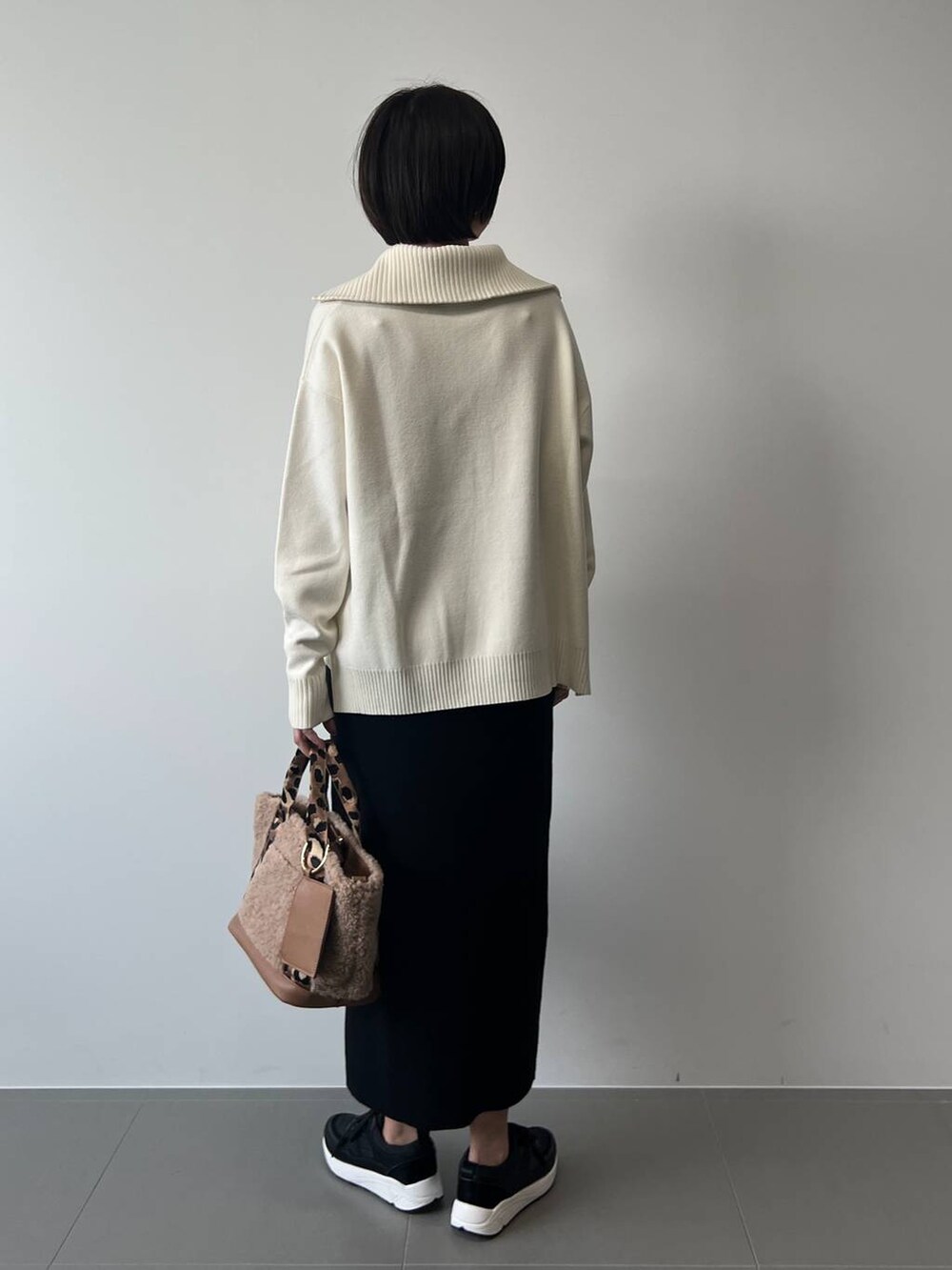 ブラウン系のトートバッグ、ブラック系のスカート、ブラック系のスニーカーを着用したレディースの冬コーディネートの5枚目の写真