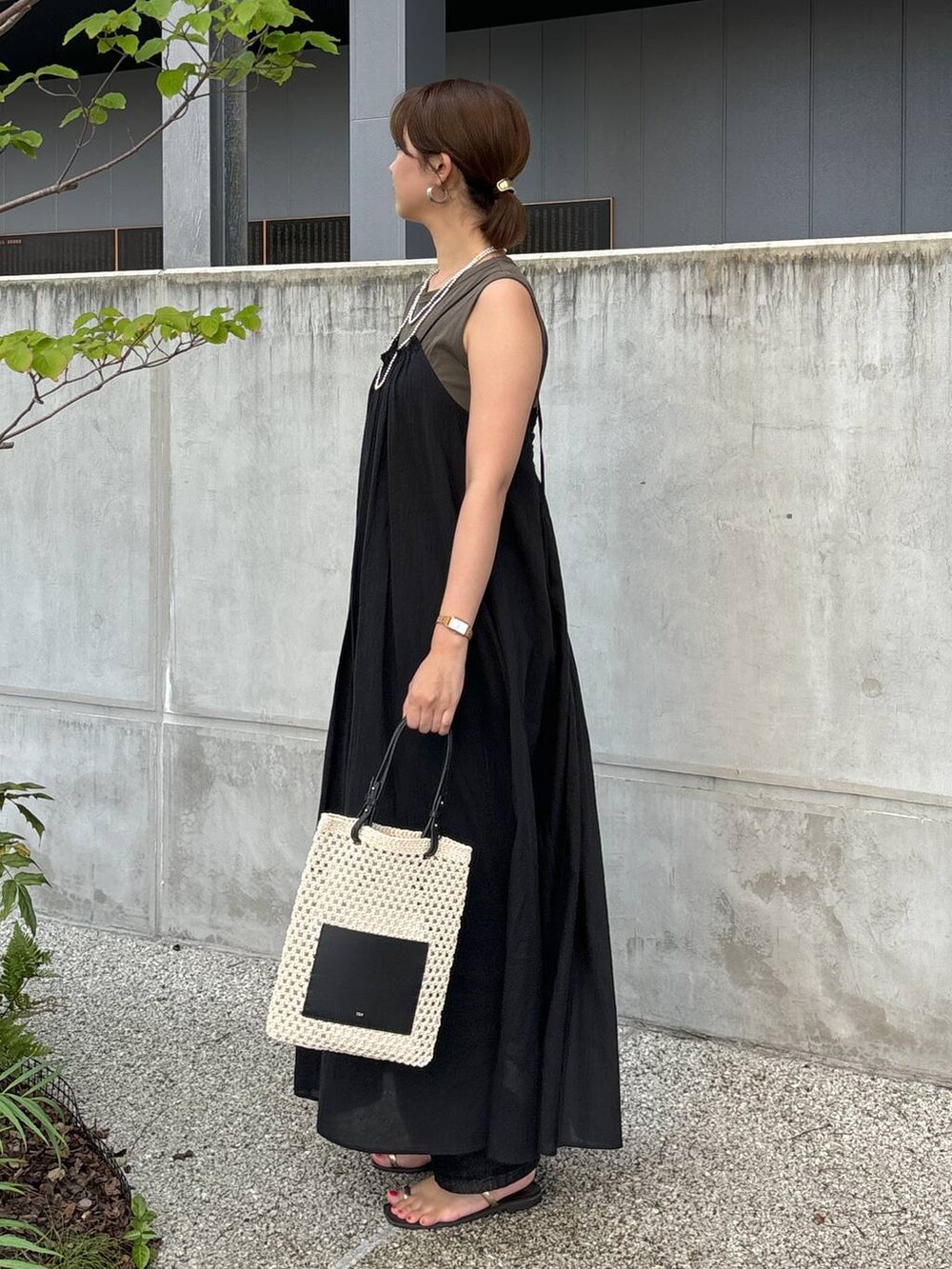 ブラック系のワンピース、ブラック系のデニムパンツ、ホワイト系のトートバッグを着用したレディースの夏コーディネートの3枚目の写真