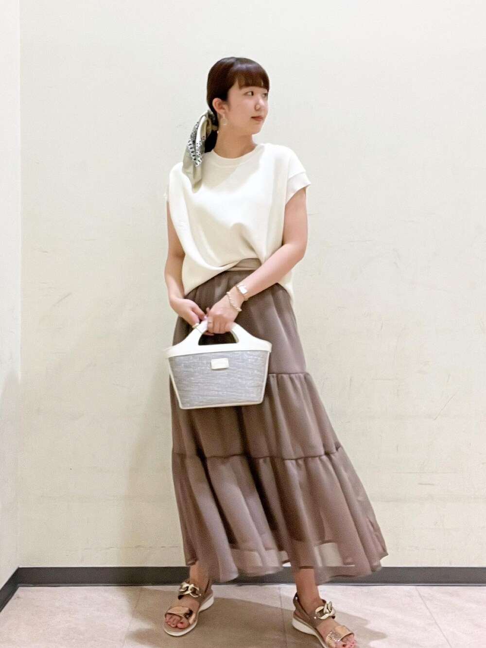 ゴールド系のサンダル、ホワイト系のニット/セーター、ブラウン系のスカートを着用したレディースの春コーディネートの2枚目の写真
