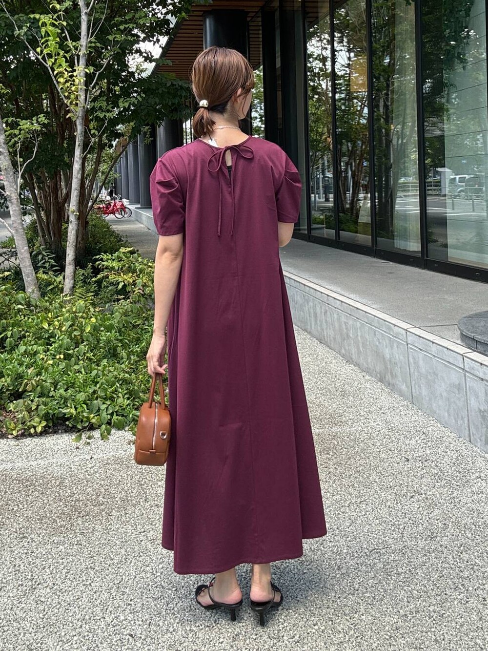 ブラック系のスリッポン、ブラウン系のハンドバッグ、レッド系のワンピースを着用したレディースの夏コーディネートの4枚目の写真