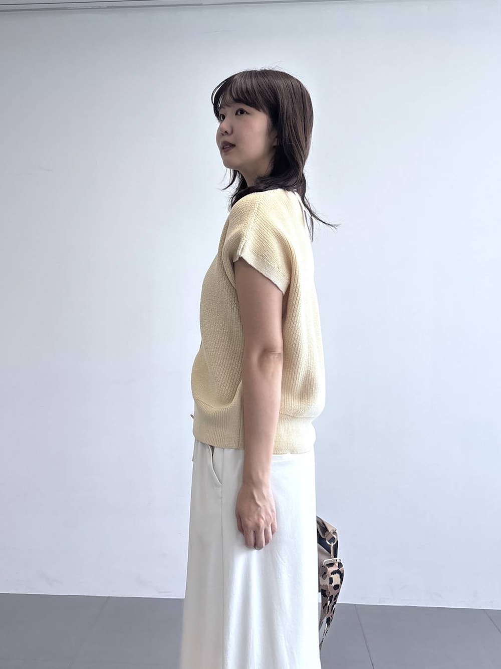 イエロー系のトートバッグ、ホワイト系のベスト、ホワイト系のスニーカーを着用したレディースの冬コーディネートの4枚目の写真