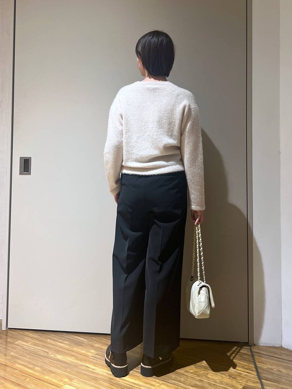 ホワイト系のショルダーバッグ、ホワイト系のニット/セーター、ブラック系のその他パンツを着用したレディースの冬コーディネートの4枚目の写真