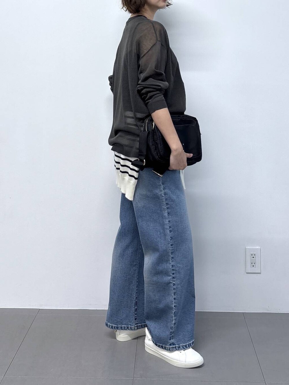 グレー系のニット/セーター、ブラック系のショルダーバッグ、ブルー系のデニムパンツを着用したレディースの秋コーディネートの6枚目の写真