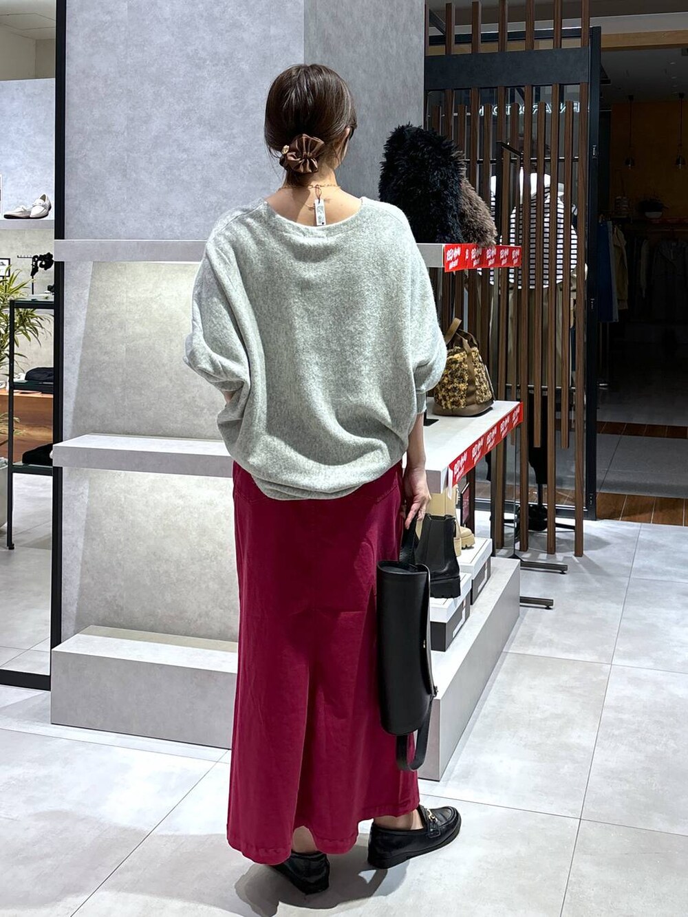 レッド系のスカート、グレー系のニット/セーター、ブラック系のショルダーバッグを着用したレディースの冬コーディネートの5枚目の写真