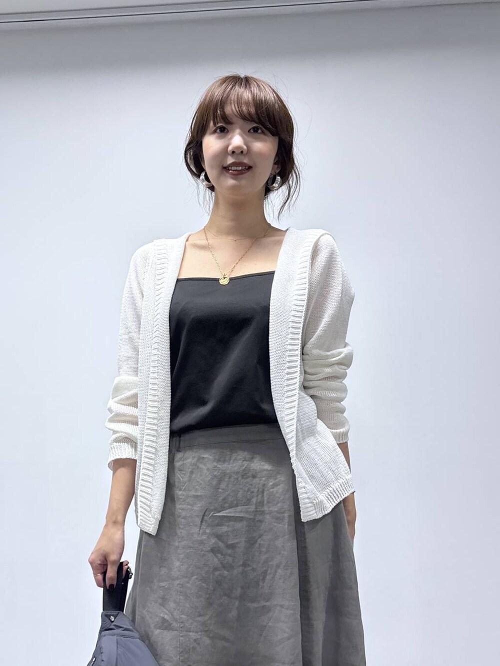 グレー系のスカート、ホワイト系のカーディガン/ボレロを着用したレディースの春コーディネートの6枚目の写真