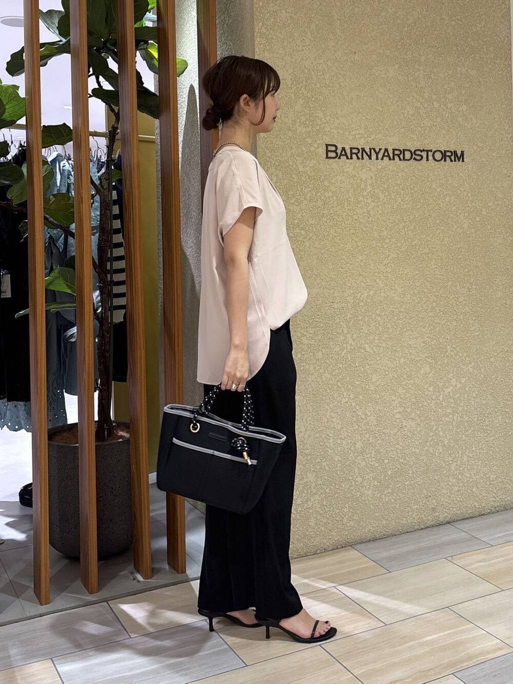 ブラック系のスラックス、ホワイト系のシャツ/ブラウス、ブラック系のトートバッグを着用したレディースの春コーディネートの5枚目の写真