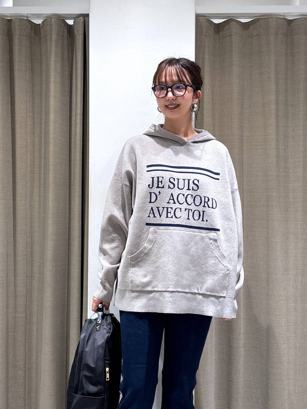 ブラック系のバックパック/リュック、ベージュ系のニット/セーター、ブルー系のデニムパンツを着用したレディースの秋コーディネートの2枚目の写真