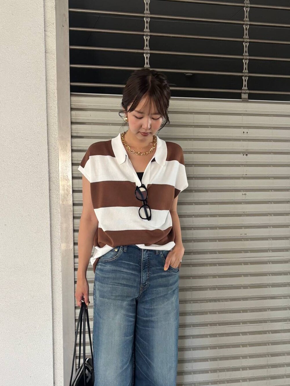 ブルー系のデニムパンツ、ブラック系のトートバッグ、イエロー系のニット/セーターを着用したレディースの夏コーディネートの4枚目の写真