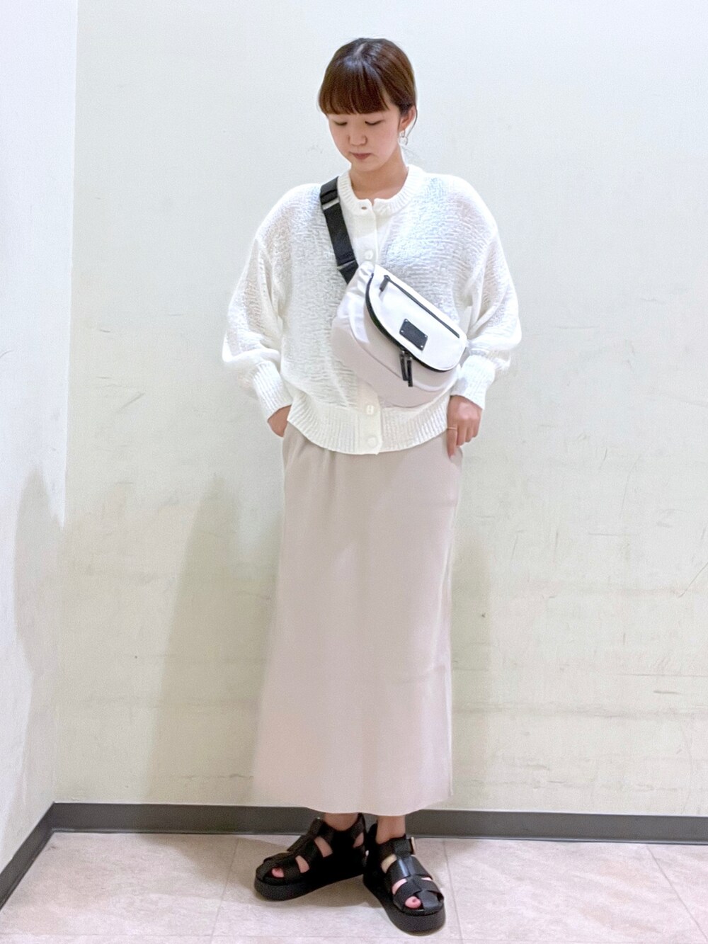 ホワイト系のショルダーバッグ、ホワイト系のニット/セーター、ブラック系のサンダルを着用したレディースの夏コーディネートの2枚目の写真