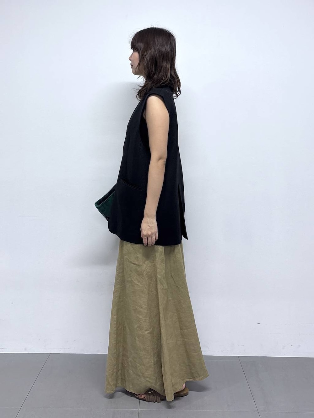 グリーン系のトートバッグ、ベージュ系のスカートを着用したレディースの春コーディネートの2枚目の写真