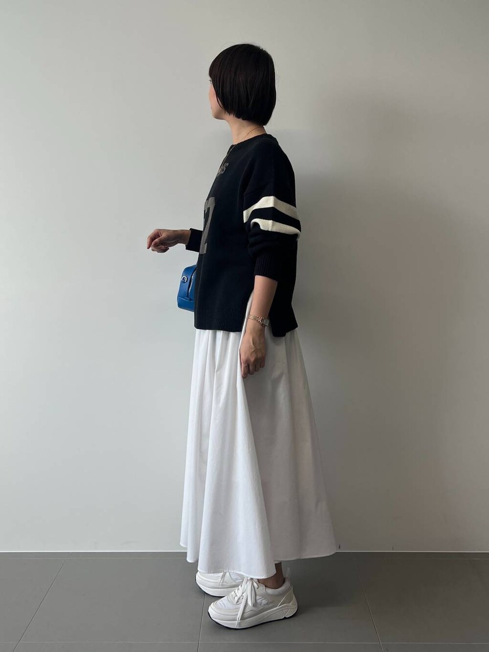 ブルー系のニット/セーター、ホワイト系のスニーカー、ブルー系のハンドバッグを着用したレディースの冬コーディネートの3枚目の写真