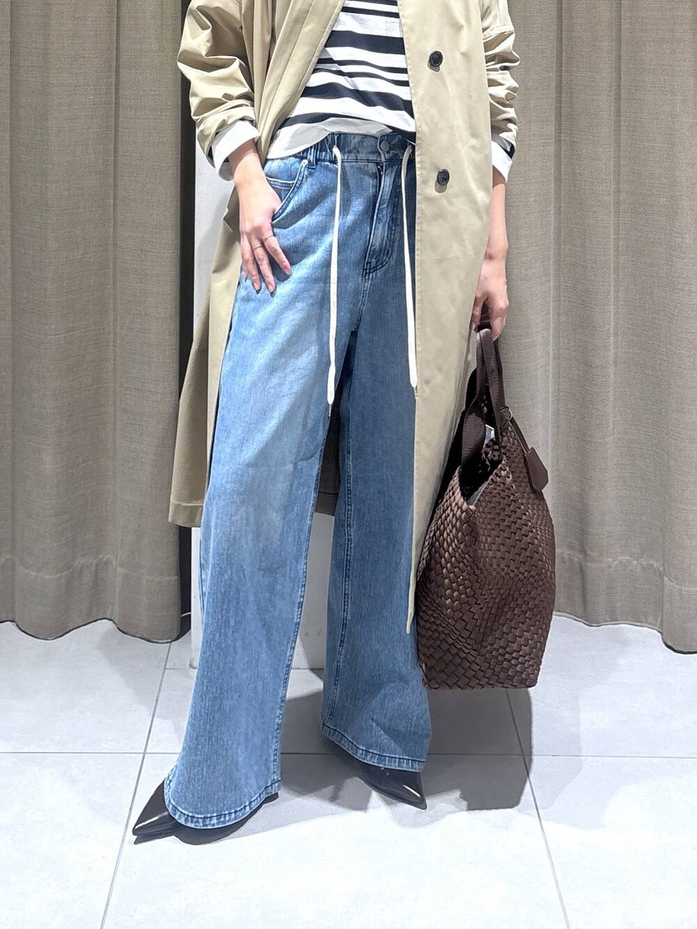 ホワイト系のTシャツ/カットソー、ブルー系のデニムパンツ、ベージュ系のステンカラーコートを着用したレディースの冬コーディネートの4枚目の写真