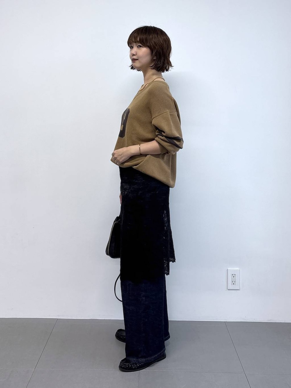 ブラック系のローファー、ブルー系のデニムパンツ、ベージュ系のニット/セーターを着用したレディースの秋コーディネートの5枚目の写真