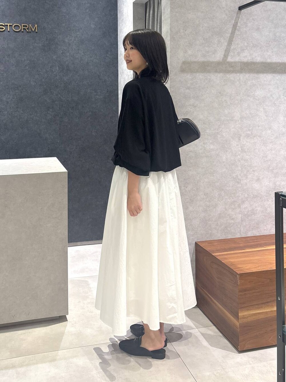 ホワイト系のスカート、ブラック系のローファー、ブラック系のボストンバッグを着用したレディースの春コーディネートの5枚目の写真