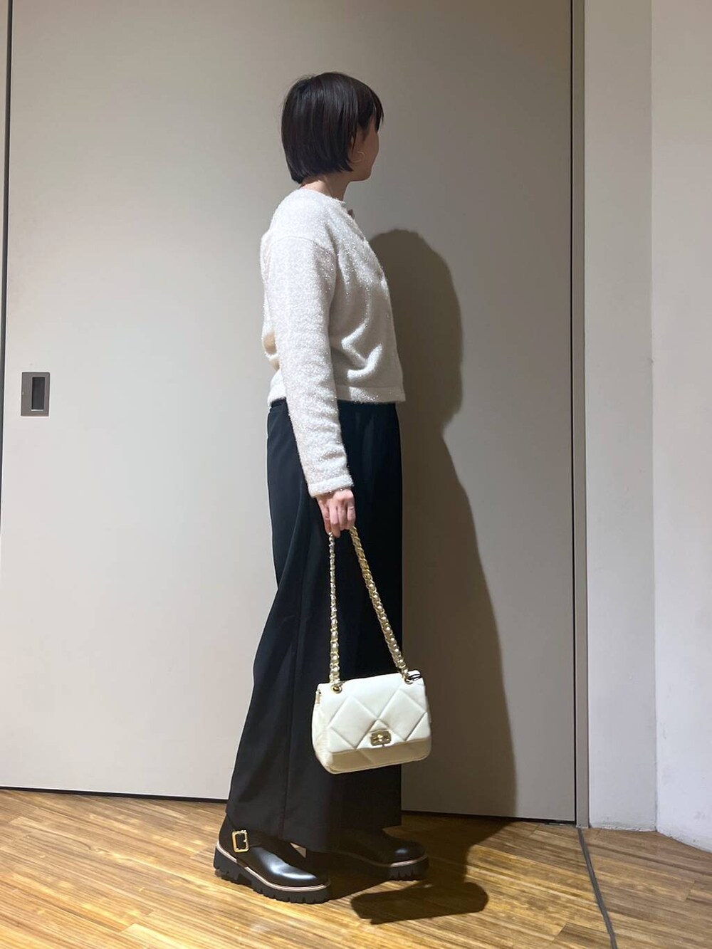 ホワイト系のショルダーバッグ、ホワイト系のニット/セーター、ブラック系のその他パンツを着用したレディースの冬コーディネートの3枚目の写真