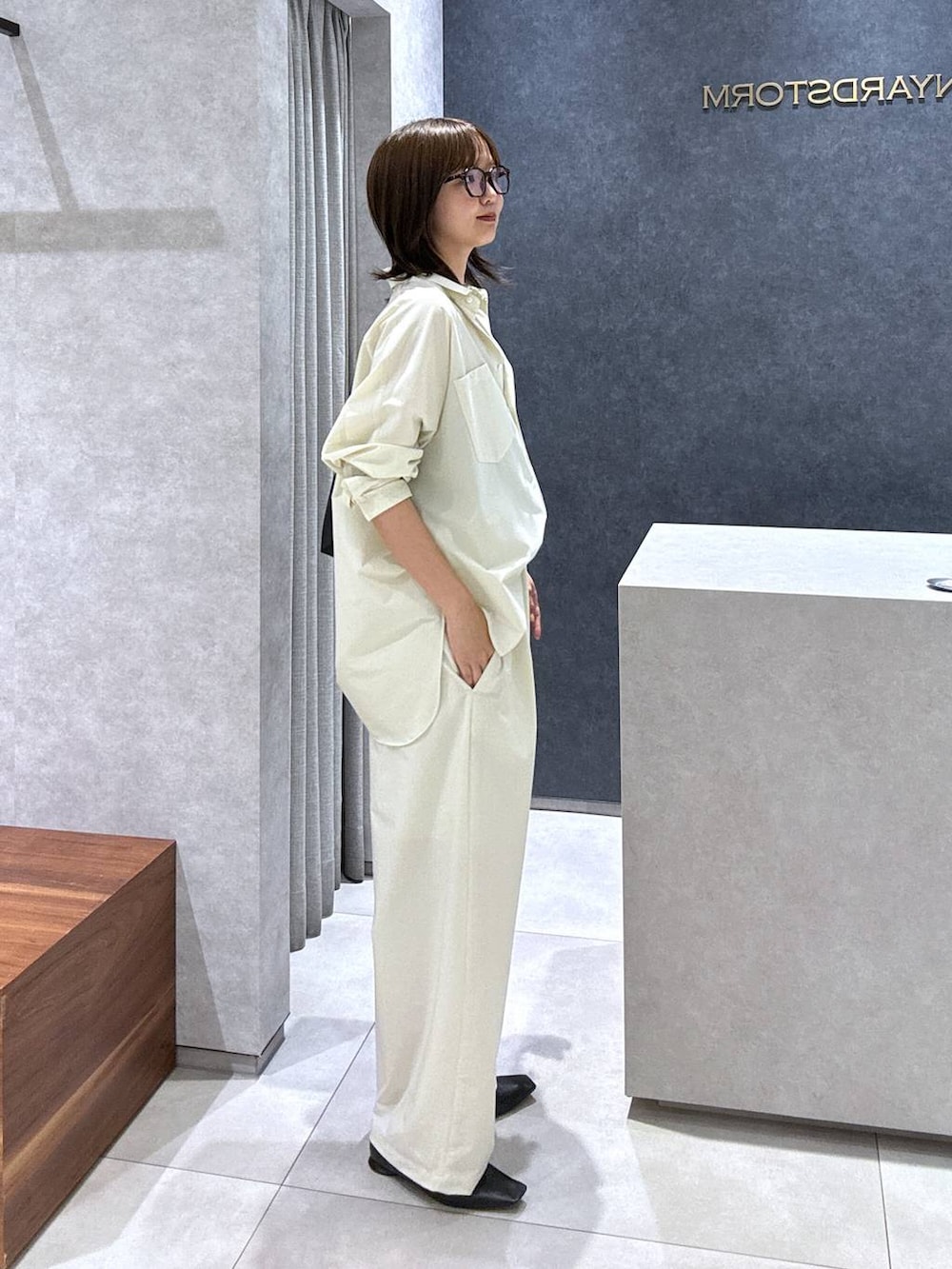 ブラック系のパンプス、ブラック系のトートバッグ、ホワイト系のシャツ/ブラウスを着用したレディースの夏コーディネートの3枚目の写真