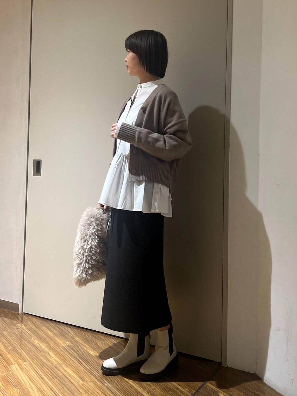 ホワイト系のブーツ、ブラウン系のハンドバッグ、ブラウン系のニット/セーターを着用したレディースの冬コーディネートの3枚目の写真