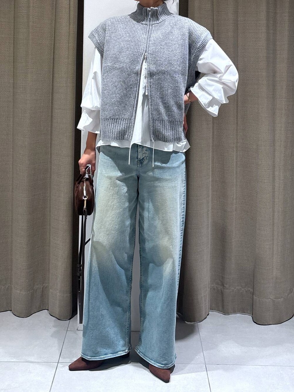 ブルー系のデニムパンツ、ホワイト系のシャツ/ブラウス、ブラウン系のショルダーバッグを着用したレディースの秋コーディネートの3枚目の写真