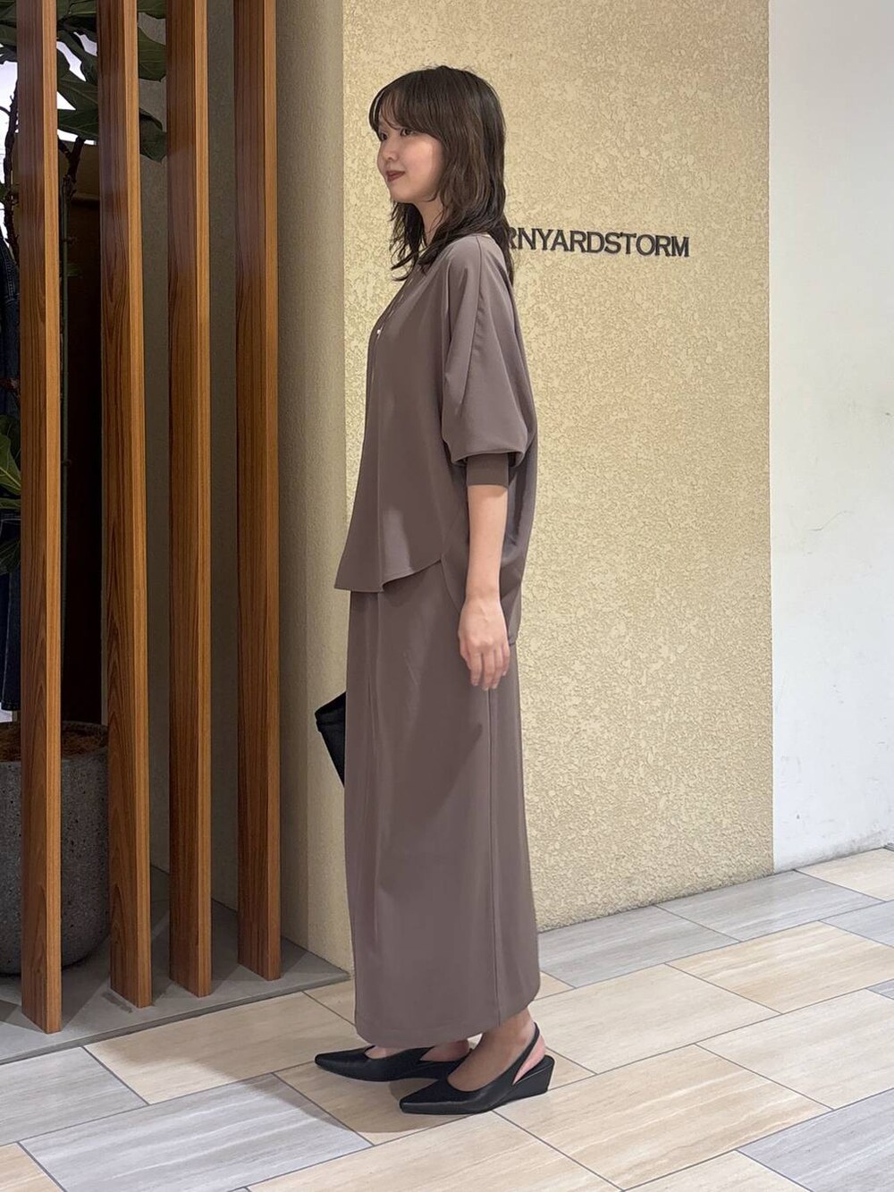 グリーン系のスカート、グリーン系のTシャツ/カットソー、ブラック系のハンドバッグを着用したレディースの冬コーディネートの2枚目の写真