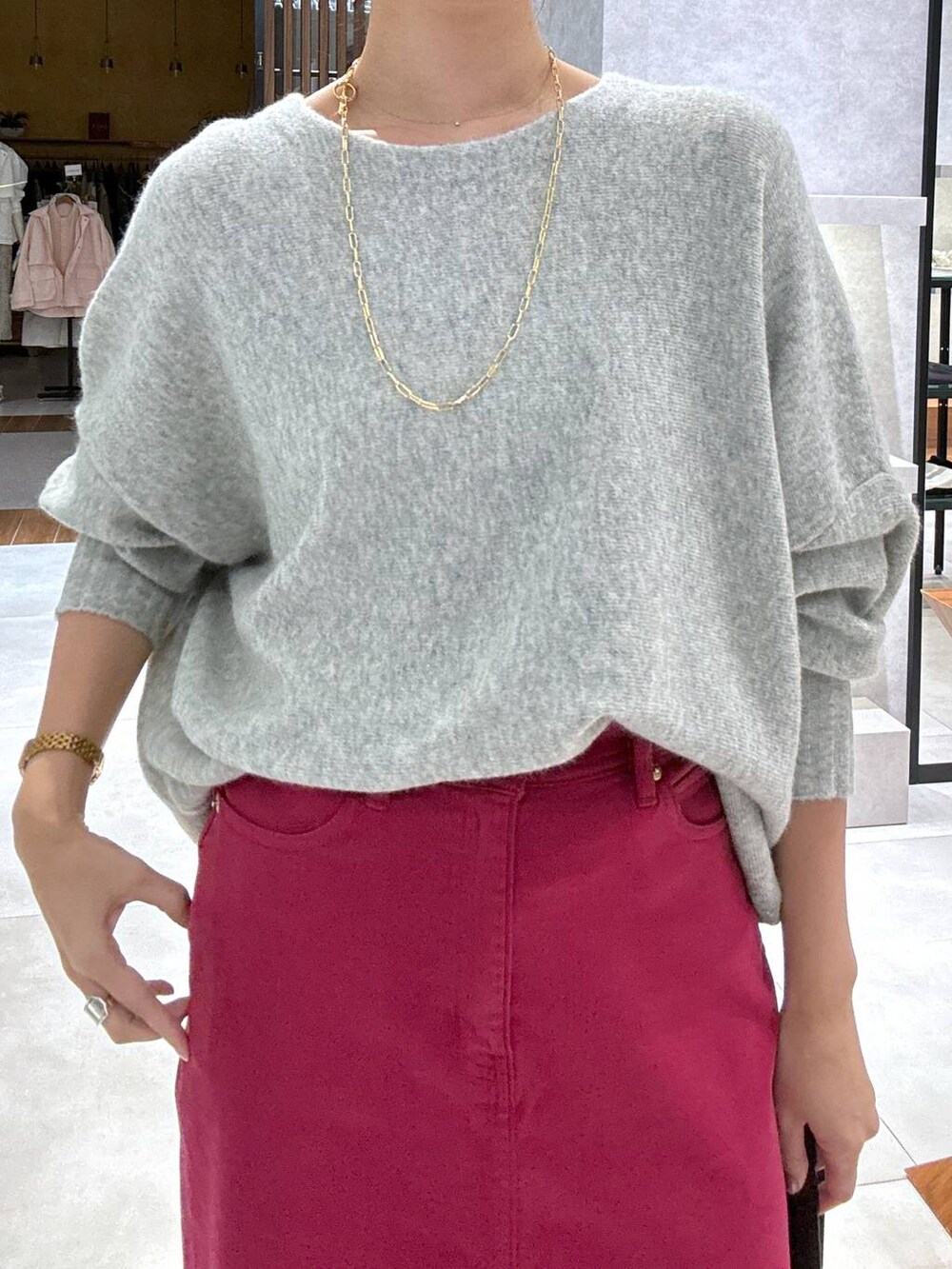 レッド系のスカート、グレー系のニット/セーター、ブラック系のショルダーバッグを着用したレディースの冬コーディネートの2枚目の写真