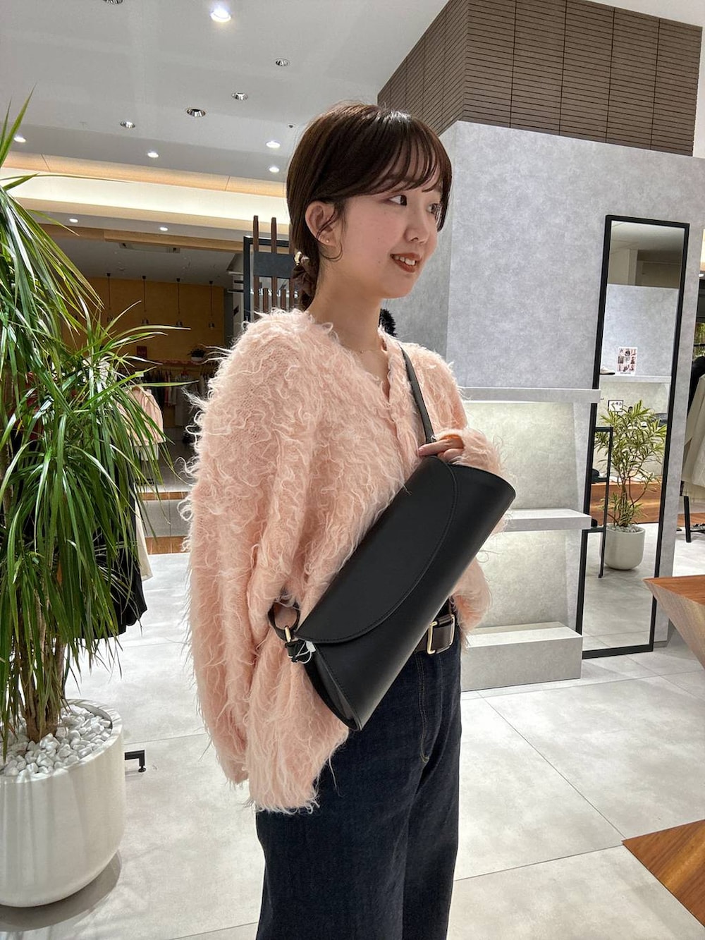 ブルー系のデニムパンツ、ピンク系のカーディガン/ボレロ、ブラック系のショルダーバッグを着用したレディースの冬コーディネートの2枚目の写真