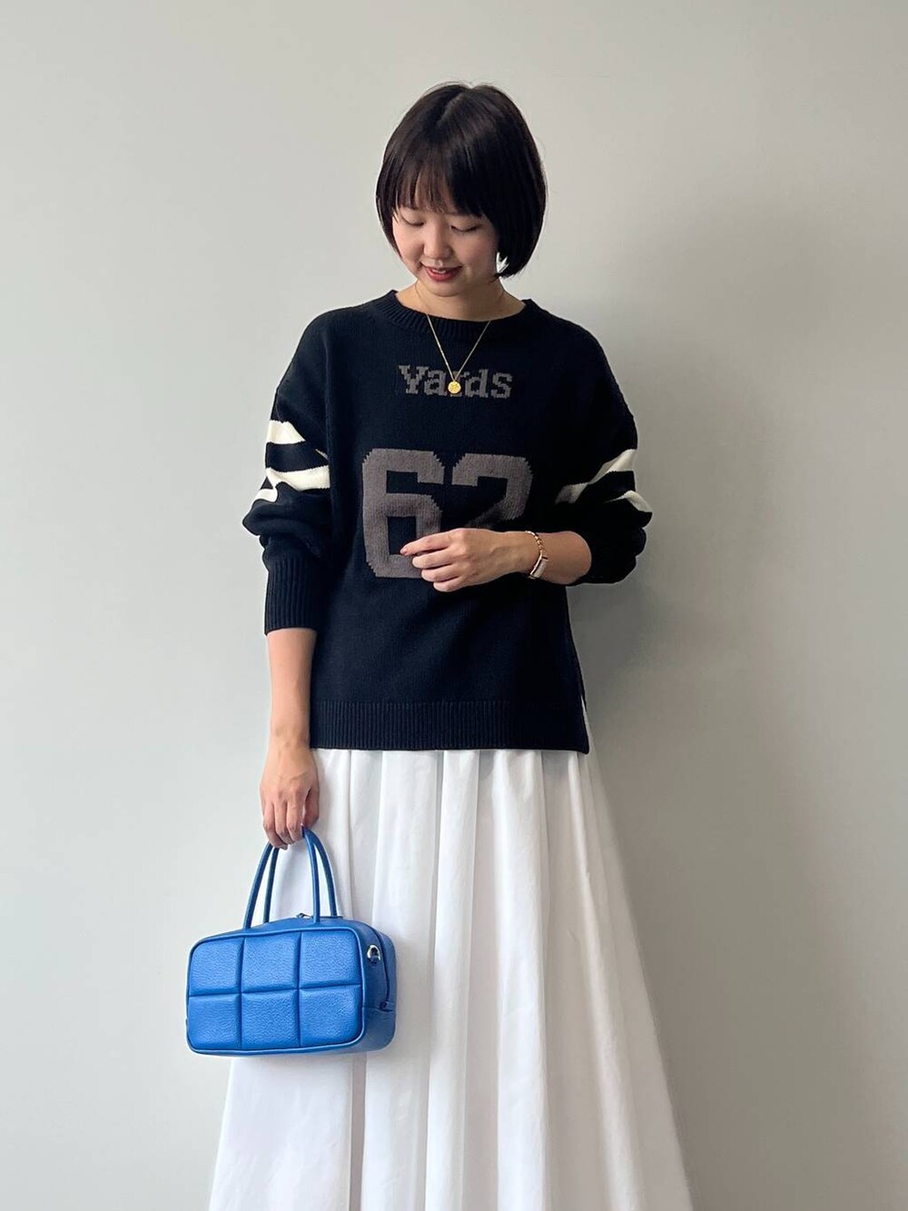 ブルー系のニット/セーター、ホワイト系のスニーカー、ブルー系のハンドバッグを着用したレディースの冬コーディネートの2枚目の写真