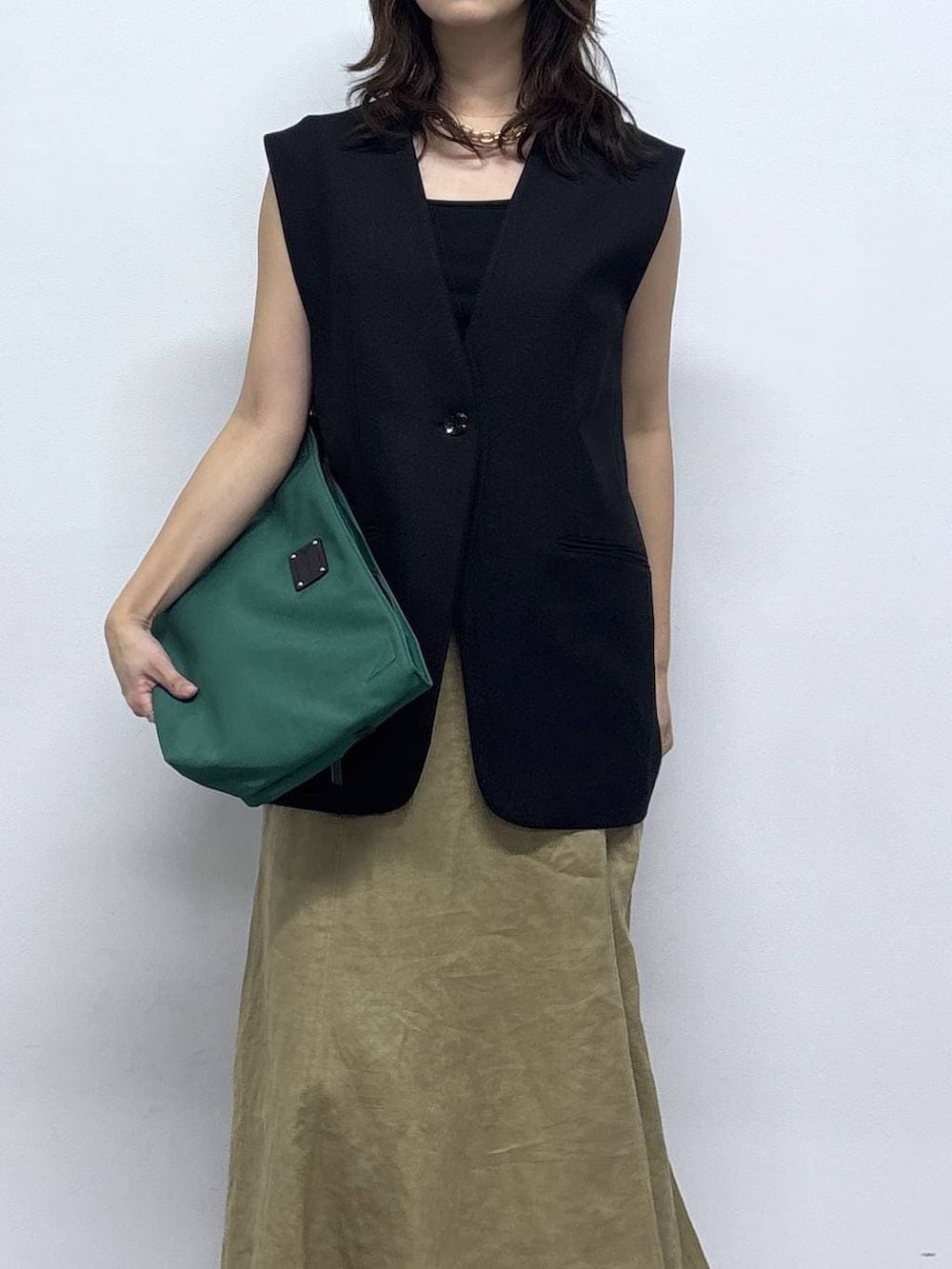 グリーン系のトートバッグ、ベージュ系のスカートを着用したレディースの春コーディネートの3枚目の写真