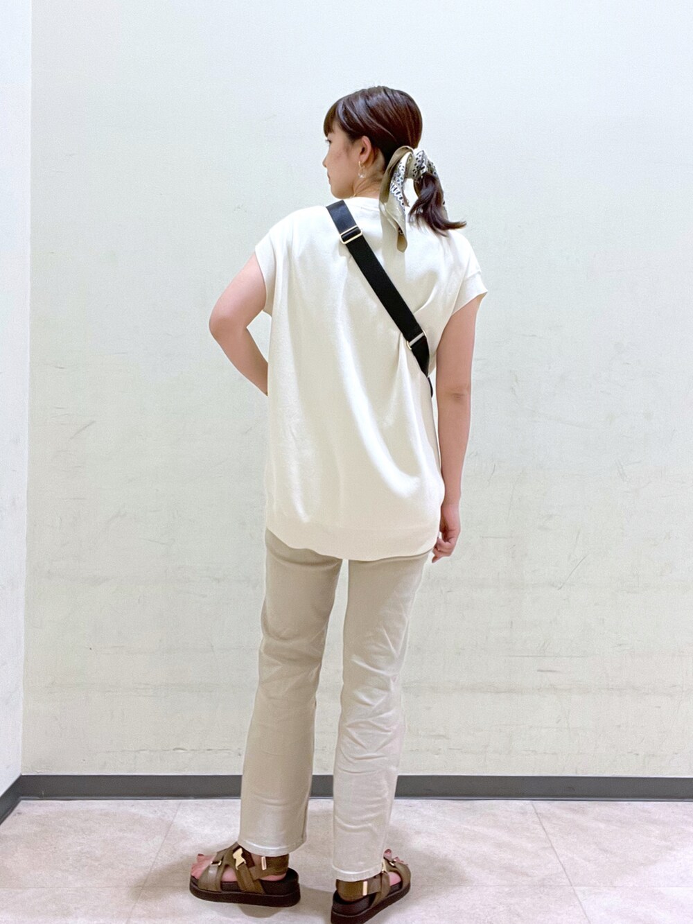 ベージュ系のデニムパンツ、ブラック系のボディバッグ/ウエストポーチ、グリーン系のシューズを着用したレディースの夏コーディネートの3枚目の写真