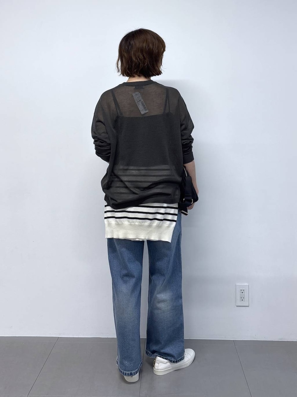 グレー系のニット/セーター、ブラック系のショルダーバッグ、ブルー系のデニムパンツを着用したレディースの秋コーディネートの5枚目の写真