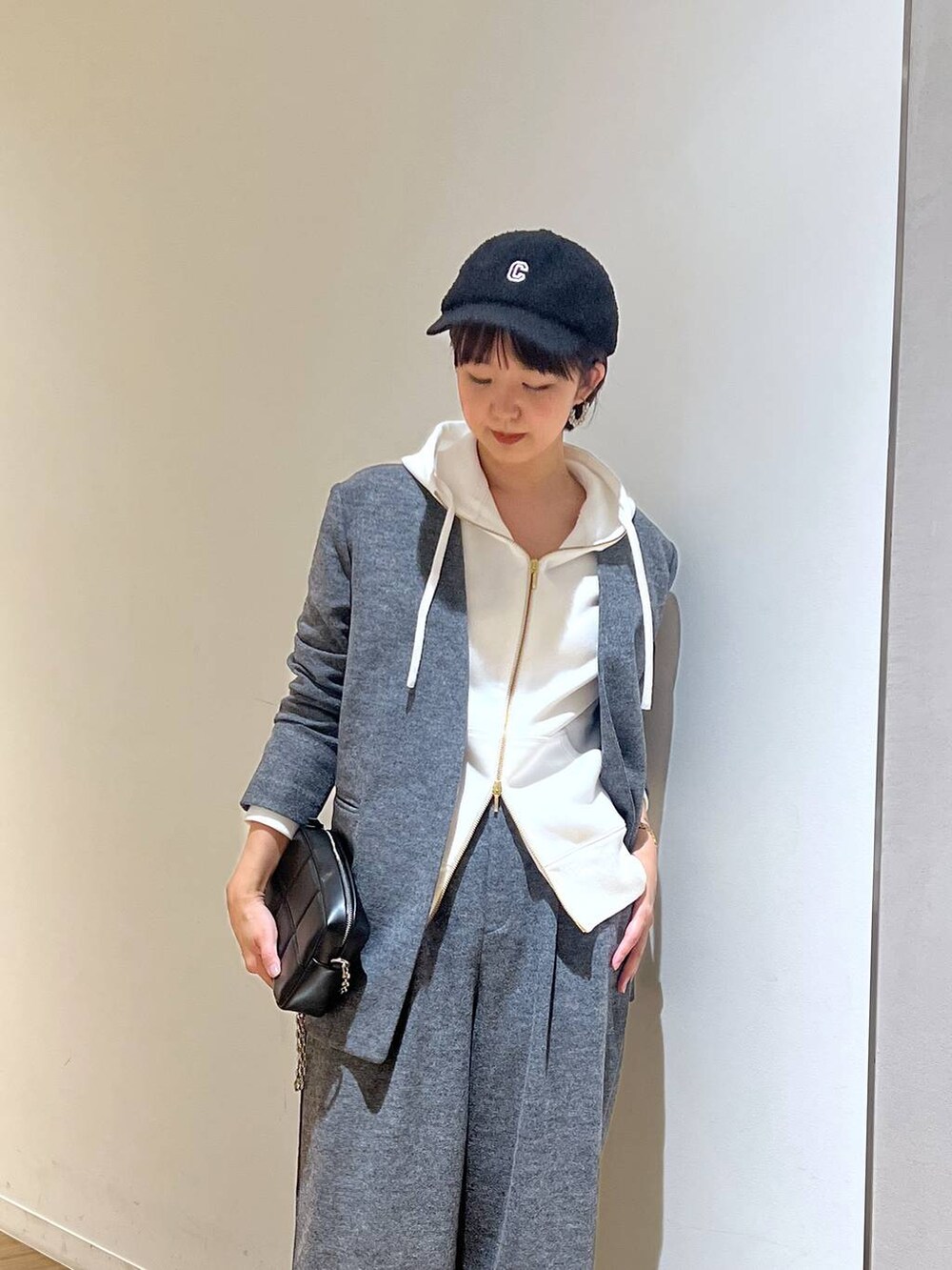ブラック系のショルダーバッグ、ホワイト系のパーカー、グレー系のスラックスを着用したレディースの秋コーディネートの2枚目の写真